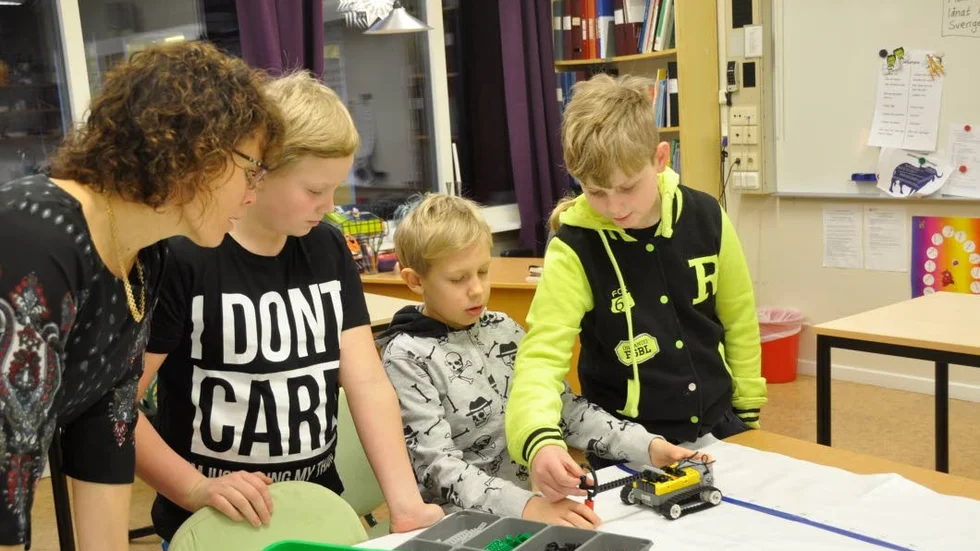 Läraren Lena Ericsson och fjärdeklassarna Matthew Peck, Valentin Claesson-Lundgren och William Nilsson kollar den bil som eleverna programmerat i datorn. Foto: Peter Frisberg