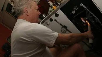 Göran Lundgren värmde sig vid köksspisen på onsdagsmorgonen.  Strömavbrott tillhör vildmarkslivet, säger den forne stadsbon.