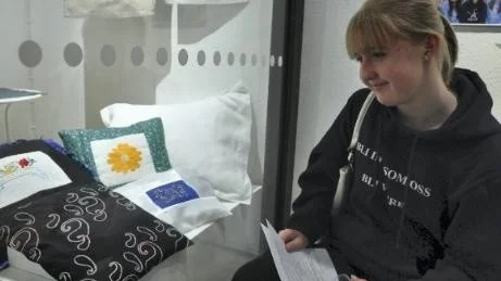 Elever från Örbyhus skola har gjort broderier som inspirerats av växterna runt de gamla soldattorpen i Tegelsmora socken. Nu visas de på Upplandsmuseet. *** Local Caption *** STOLT. Visst har man anledning att vara stolt när ens broderier visas på Upplandsmuseet. Martina Odenius har bidragit med kudden i svart broderad med förstygn.