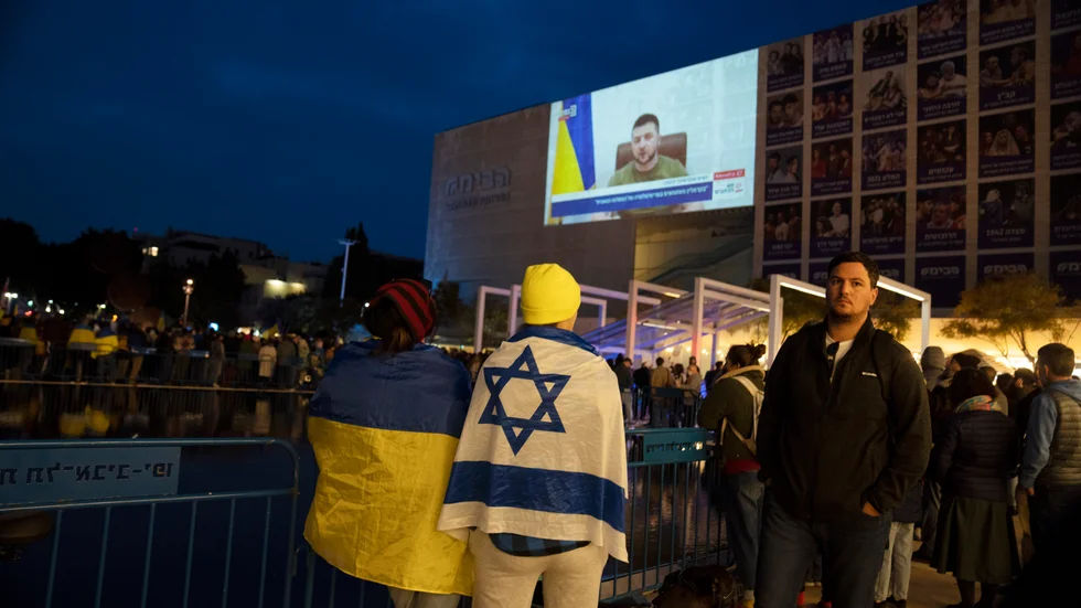 Människor följer Volodymyr Zelenskyjs tal på ett torg i Tel Aviv, Israel.