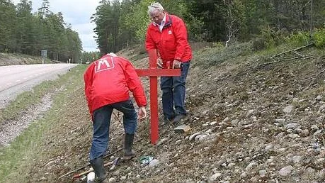 Lars Andersson och Lennart Bork från Motormännen reser ett kors vid riksväg 67.