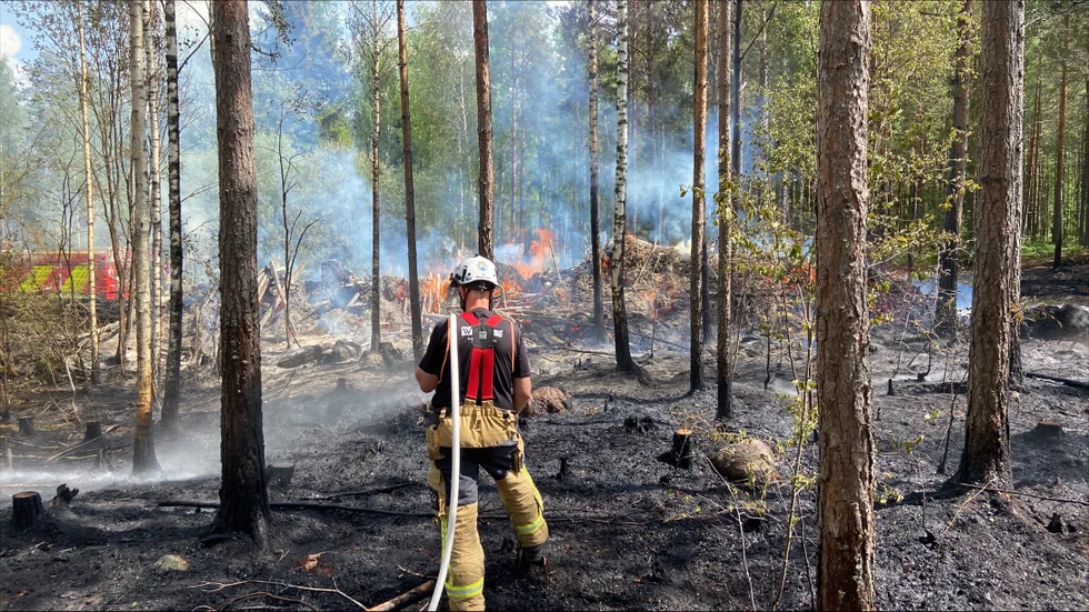 En brandman lägger på vatten i brandområdet.