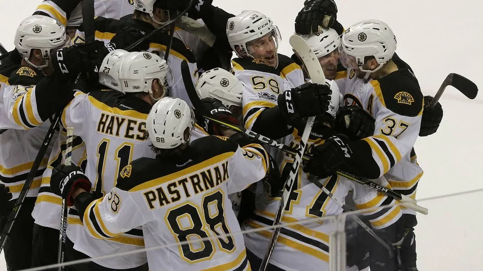Boston Bruins left wing Brad Marchand, second from top right, celebrates with teammates after scoring the winning goal against the San Jose Sharks.
