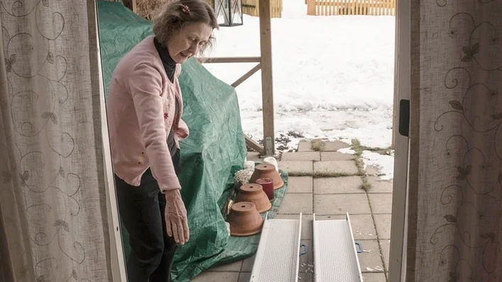 Magdalena Rangne har fått två stycken skidor som enkelt går att montera på ytterdörr och trädgårdsdörr. Med de har hon kunnat rulla upp sin man Ingmar för tröskeln, när han har varit hemma.