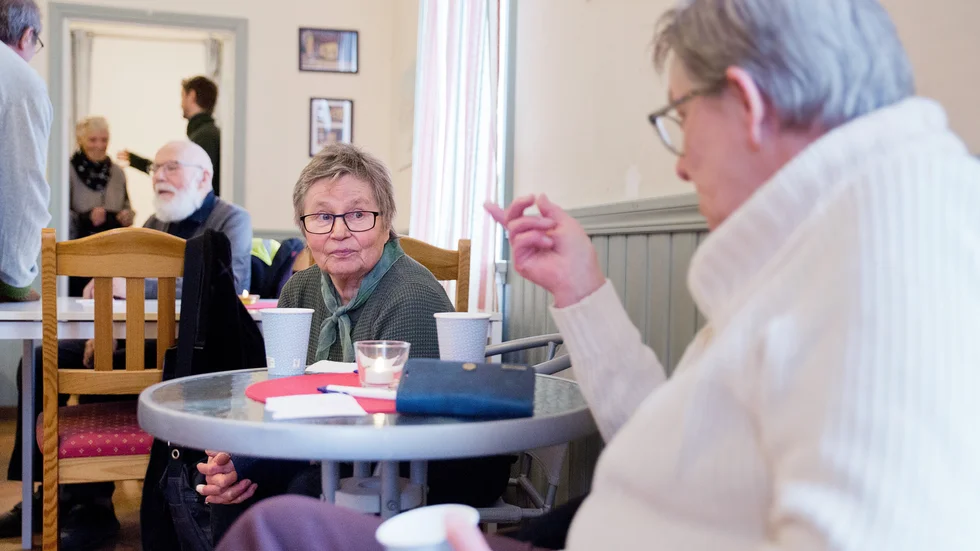 Anna-Lisa Andersson från Eke och andra som fikar och väntar på sin tur, i det gamla stationshuset i Hemse. Genom dörren kommer Inga-Maj Häglund ut från castingrummet.