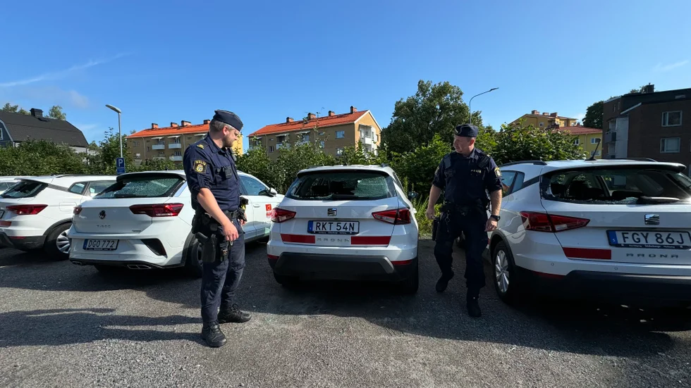 Christian Söderholm och Rickard Fahlén från polisen i Finspång vid bilarna som fått sina bakrutor krossade. 