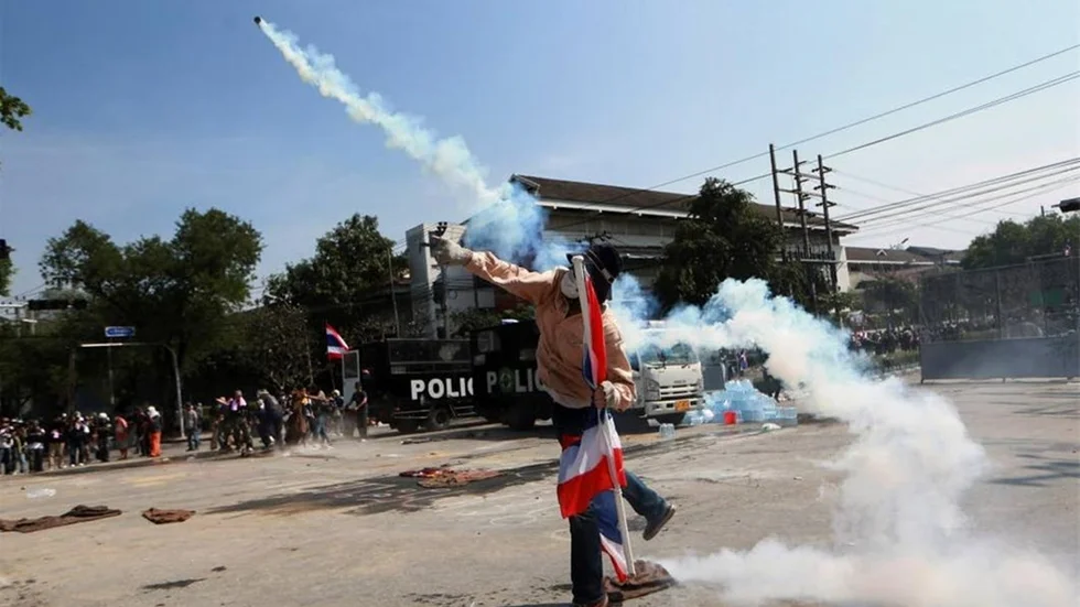 TÅRGAS. Demonstranter kastar tillbaka tårgasampullerna mot polisen i Bangkok.