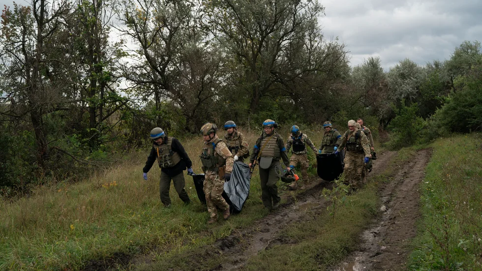 Ukrainska soldater bär undan säckar med kvarlevor av två landsmän, i ett område nära ryska gränsen i Charkiv-regionen. Bilden togs i måndags.