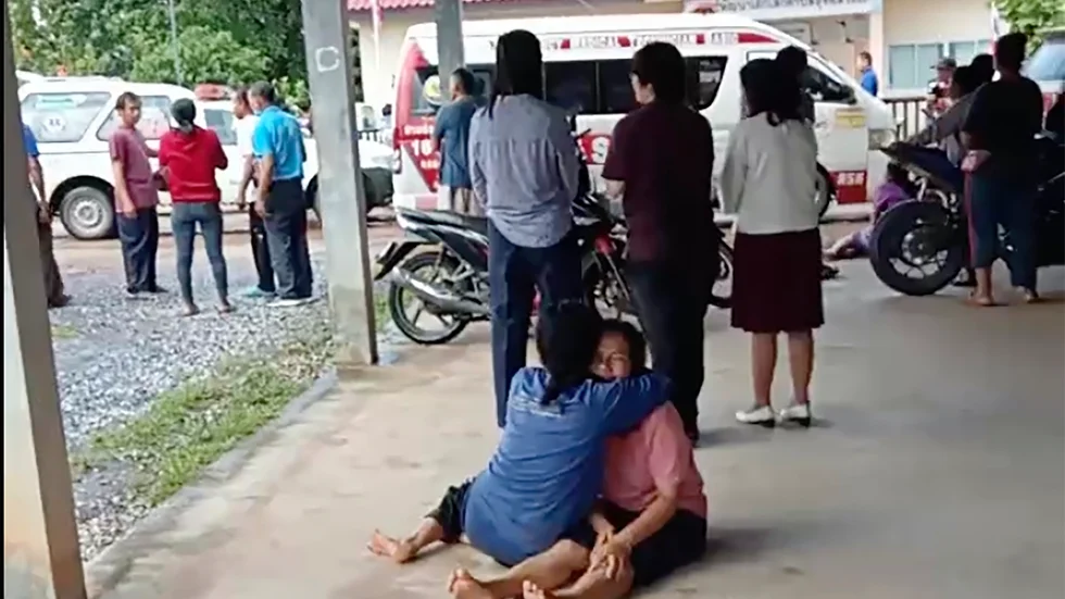 En stillbild från en video visar hur en uppriven kvinna tröstas utanför förskolan i norra Thailand.