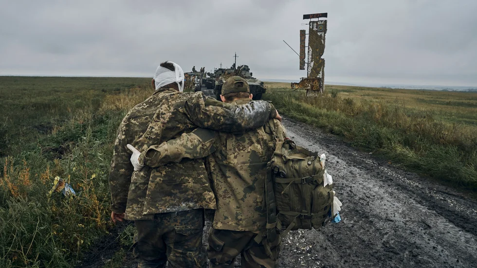 En ukrainsk soldat hjälper en sårad kollega.