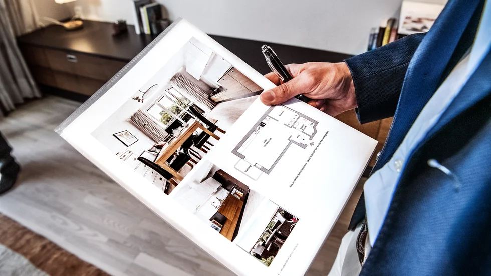 En mäklare med ett informationsblad om en bostadsrätt som är till salu.