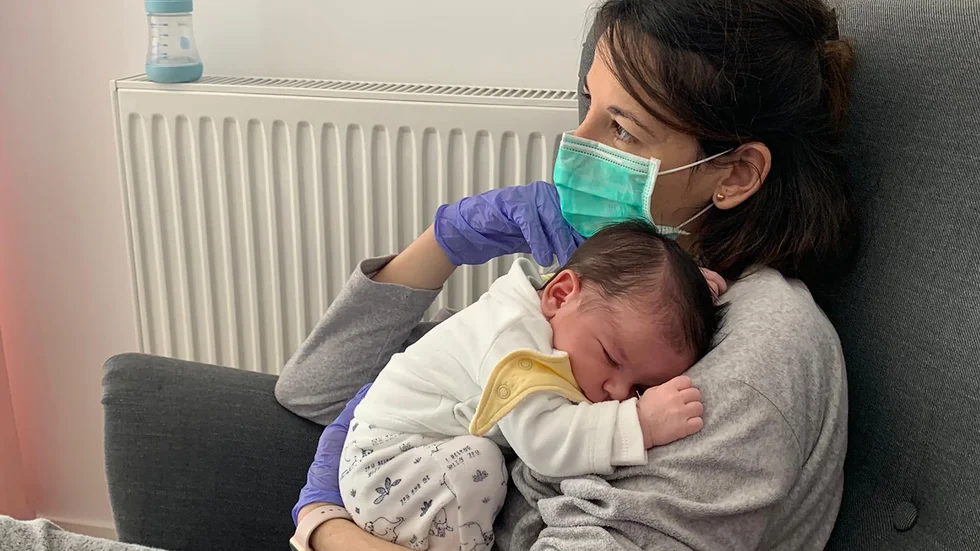 Vanesa Muro i Madrid håller sin nyfödde son Oliver. Än har hon, eller barnets pappa Oscar Carrillo, inte kunnat röra vid sonen utan plasthandskar av rädsla för att smitta honom med coronaviruset.