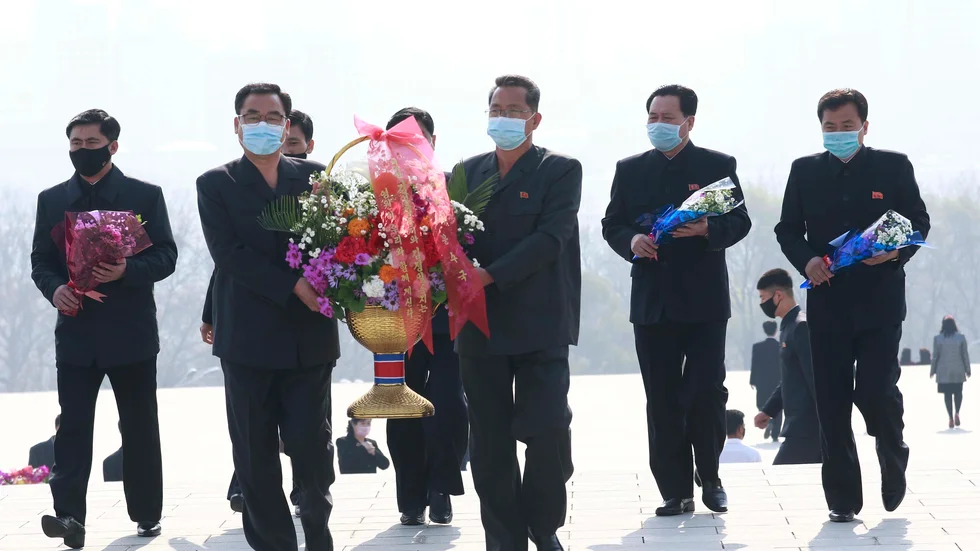 Nordkoreaner i munskydd lägger ner blommor vid den avlidne ledaren och diktatorn Kim Il-Sungs staty i veckan.