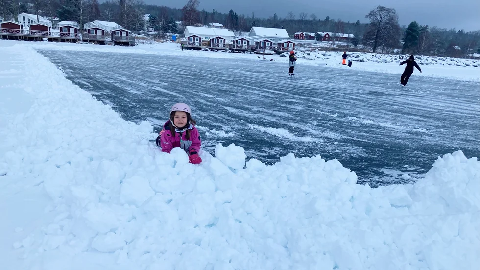 Olivia Hjelm leker i snöhögarna i förgrunden. 
