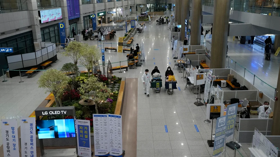 Två passagerare lotsas rätt av karantänpersonal vid flygplatsen Incheon i Sydkorea.
