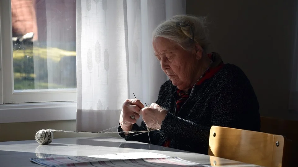 Elsie Nilsson sitter i det härliga och varma solskenet och stickar på sockar innan mötet påbörjas. Foto: Morgan Karlsson