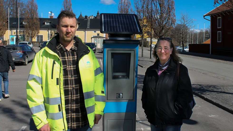 Hugo Andersson. enhetschef gata och park på Motala kommun och Caroline Unéus, ordförande för samhällsbyggnadsnämnden flankerar den nya parkeringsautomaten på Hamnparkeringen i Motala.