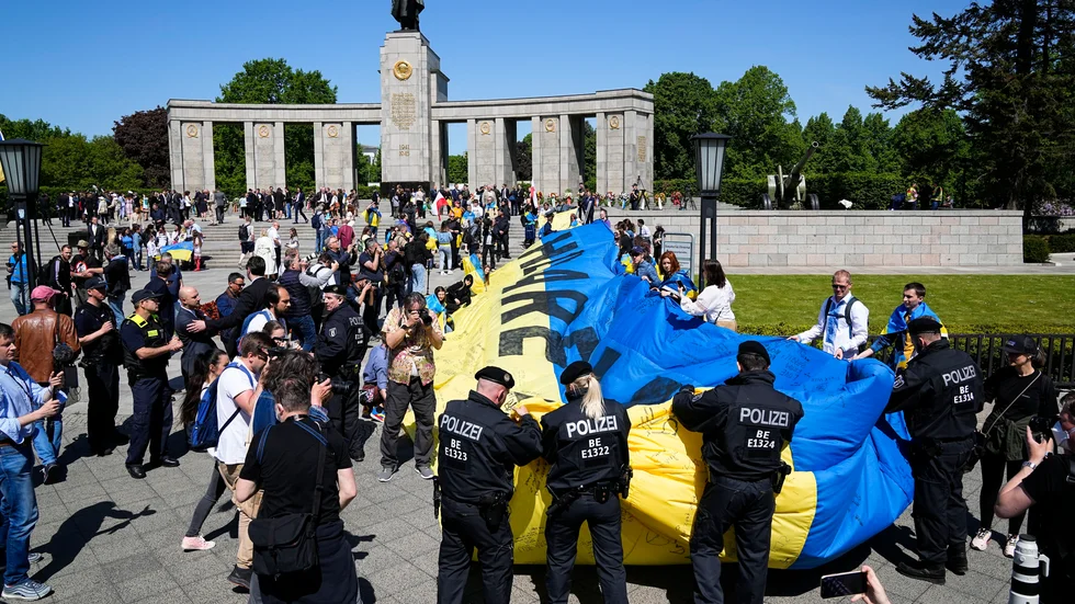 Polisen i Berlin rullar ihop en stor ukrainsk flagga som vecklades ut vid ett sovjetiskt minnesmonument under söndagen.