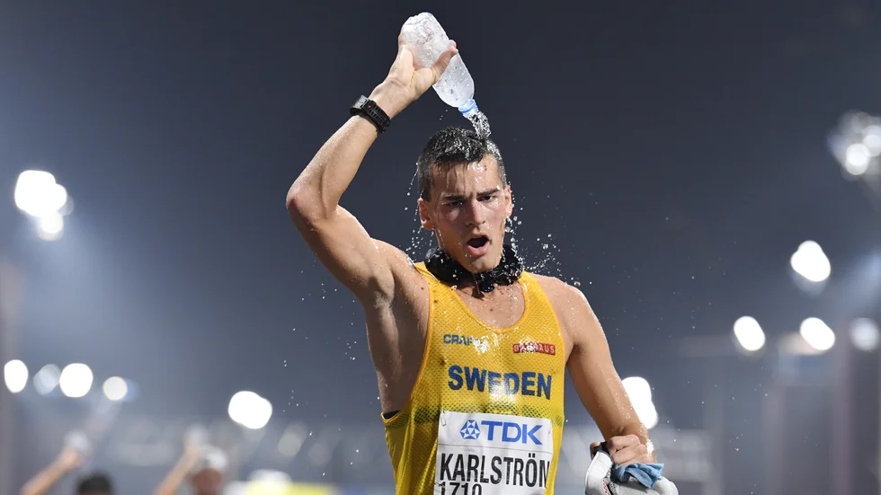 Perseus Karlström – med "iskorven" runt halsen – svalkar sig med vatten under gångtävlingen i friidrotts-VM i Doha 2019. Arkivbild.