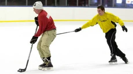 Jocke Andersson i gul tröja försöker få stopp på Robin Fors, med hjälp av klubban. En incident i stridens hetta i den dock mycket vänskapliga hockeymatchen i Globalhallen med sportlovslediga och arbetslösa ungdomar. Foto: Robert Svensson