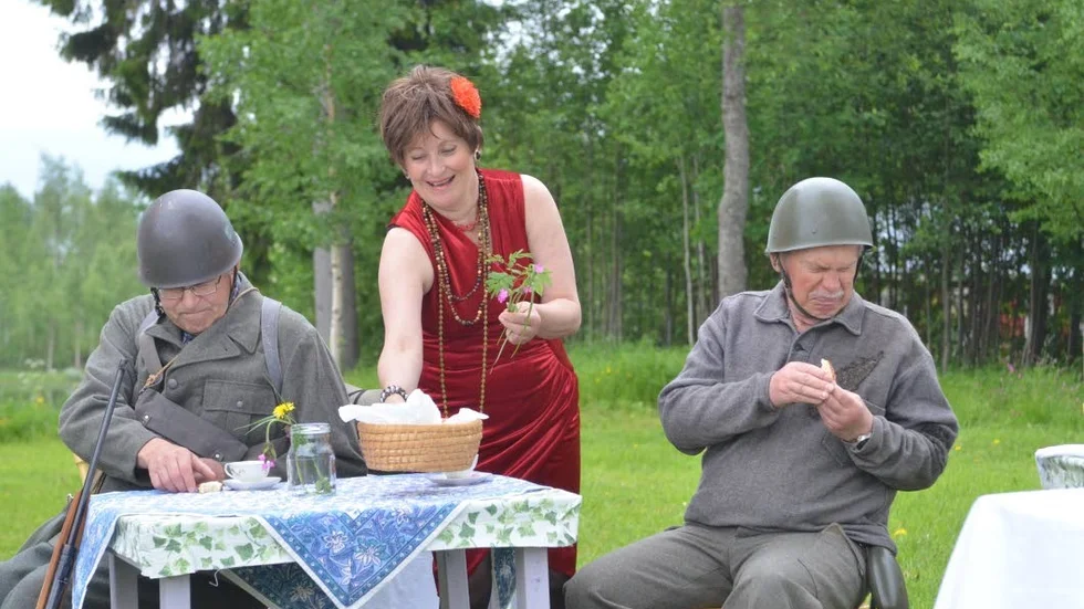 Sommarteater. Två soldater bjuds på fika på Annas kafé. Att döma av minerna på herrarna så smakar nog bullarna inte mumma.