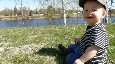 Olle Pettersson, 10 månader, myser hemma på gräsmattan i Nygård. Piteälven i bakgrunden.