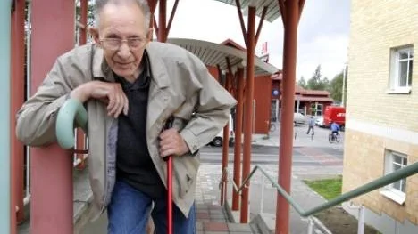 Sigurd Öhman, 90, visar hur en av tjuvarna hängde över trappräcket för att liksom blockera vägen. En annan person kom bakifrån och slet till sig 90-åringens plånbok. I bakgrunden syns ICA där Öhman hade varit och handlat.