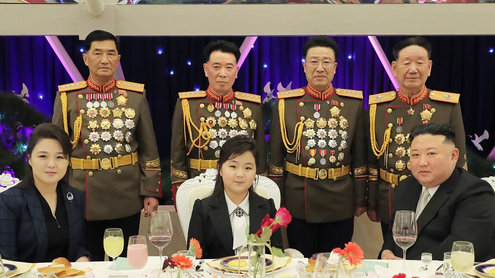 Vid bordet, från vänster: Diktatorsfrun Ri Sol Ju, dottern Kim Ju-Ae och diktatorn själv, Kim Jong-Un. Bakom dem står flera höga ledare inom militären. Bilden har distribuerats av Nordkorea via landets propagandamedier.