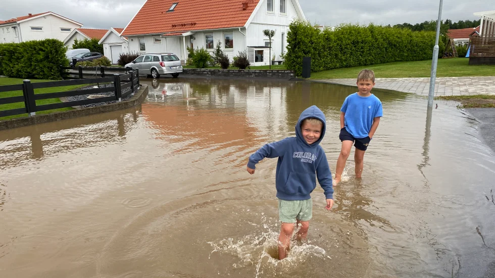Melwin och Kasper Palmgren testar vattendjupet på gatan utanför familjens villa i Mantorp. Familjen har klarat sig relativt lindrigt undan jämfört med flera grannar.