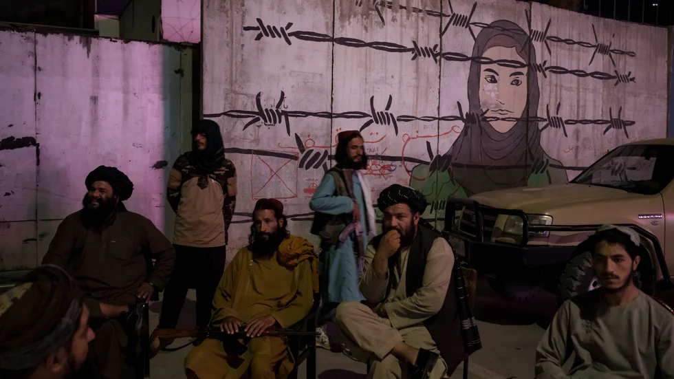 En grupp talibaner i samtal framför en väggmålning i Kabul. Arkivbild.