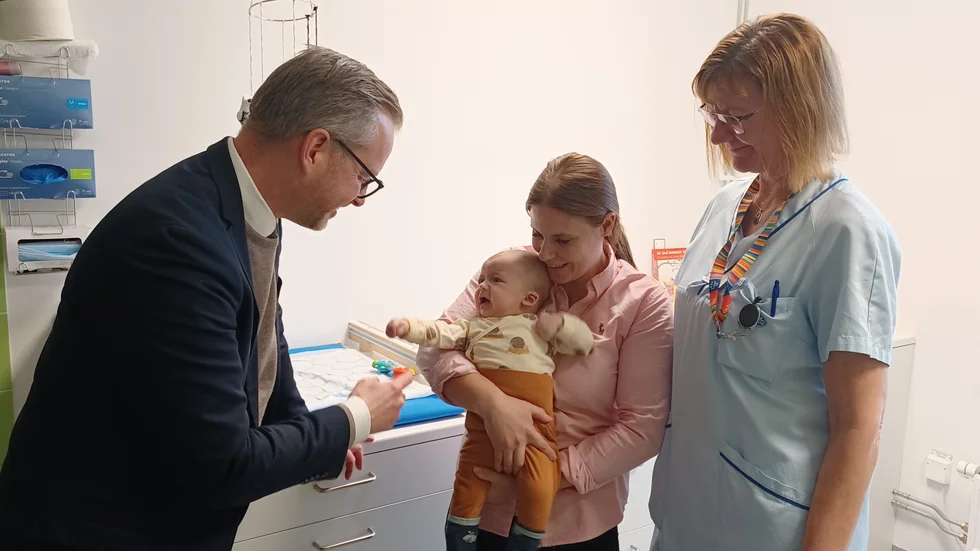 Finansminister Mikael Damberg i samspråk med Frank Olah Sege, hans mamma Julia Olah och sköterskan Anne Samuelsson på Sandbyhovs barnavårdscentral. 