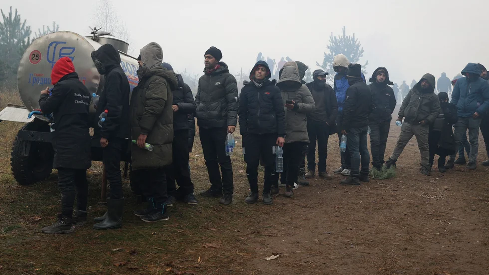 Migranter köar för att få dricksvatten vid gränsen mellan Belarus och EU-landet Polen.