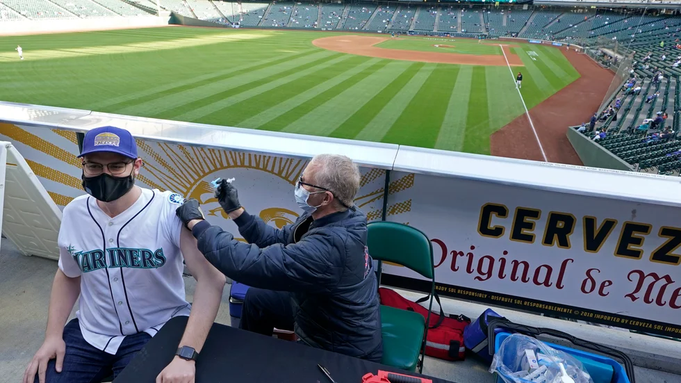 Den avtagande vaccinationstakten i USA oroar, men här får Seattle Mariners-supportern Hunter Moreira sitt covidvaccin före basebollmatchen mot Baltimore Orioles.