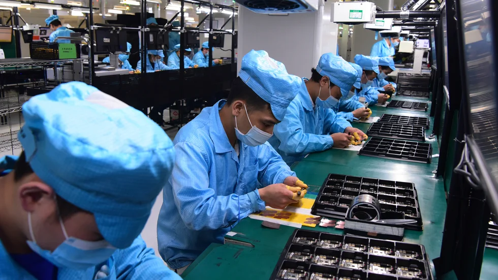 Anställda på en telekomfabrik i Dongguan med munskydd. Bilden är från förra året – nu inleder industristaden masstestning.