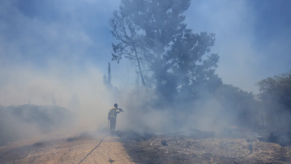 En israelisk brandman försöker släcka en brand som orsakats av ballonger från Gazaremsan under tisdagen.
