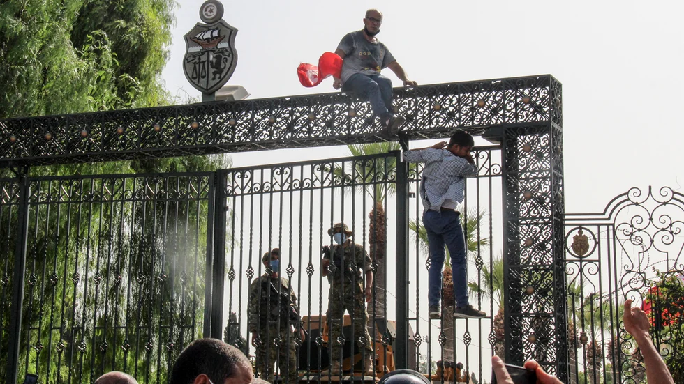 Tunisiska soldater vaktar huvudentrén till parlamentsbyggnaden i Tunis medan demonstranter samlas utanför.