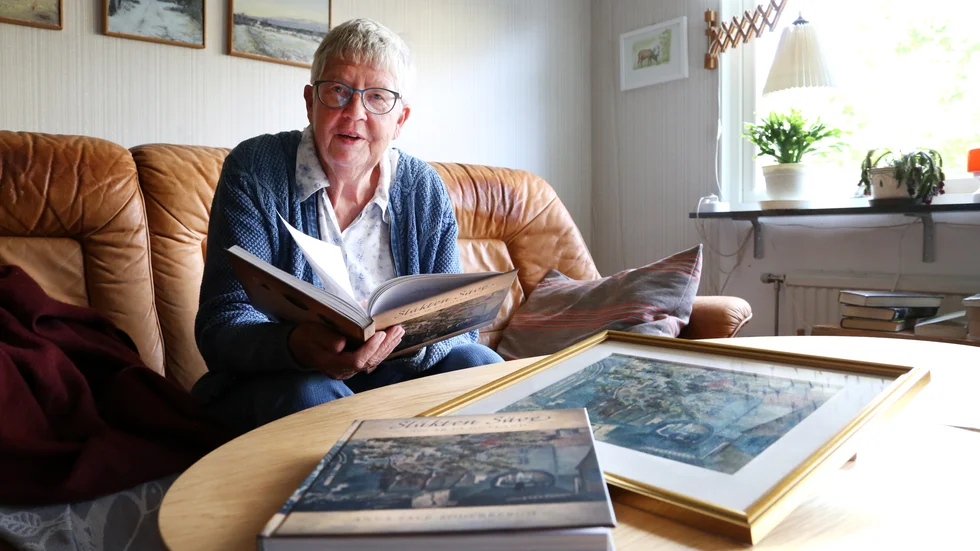 Anna Säve-Söderbergh i hemmet med boken och tavlan som utgör omslagsbilden. 
