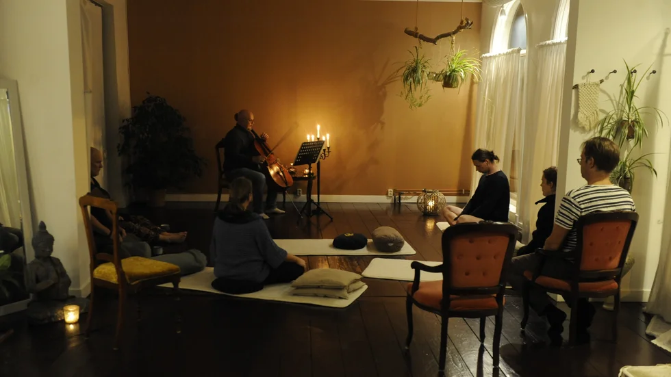 Erik Berg spelar cello. Deltagarna dricker te och lyssnar. 