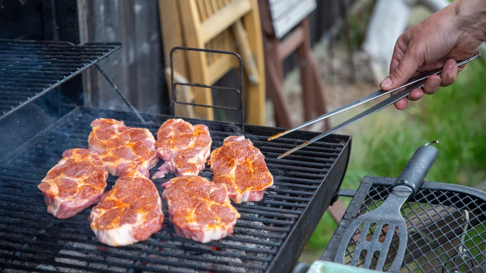 En man grillar kött.