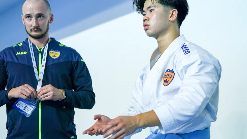 Assisterande landslagscoachen Felix Falk försöker trösta Anthony Vu efter att flera domslut gått emot 17-åringen från Karate Dojo i en av världens största tävlingar.