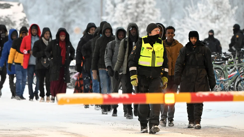 Finska gränsvakter eskorterar migranter vid gränsövergången i Salla på torsdagen.