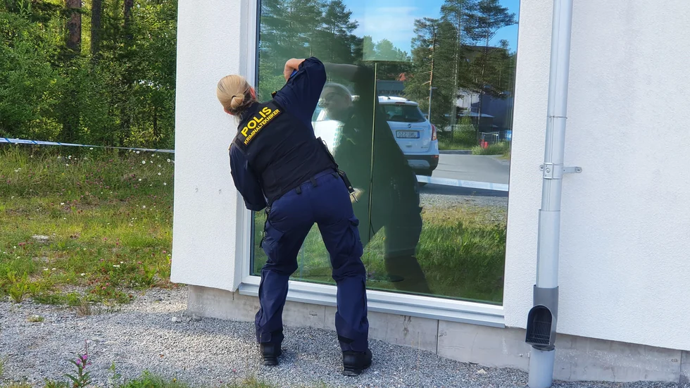 En av polisens kriminaltekniker undersöker rutan.