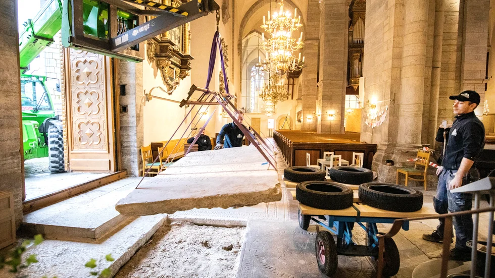 Lyftet av den 800 kilo tunga gravstenen kunde göras med hjälp av en kranbil som stod på kykans utsida. Här med hjälp av byggarbetarna Jerker Johansson och Oskar Wallin.