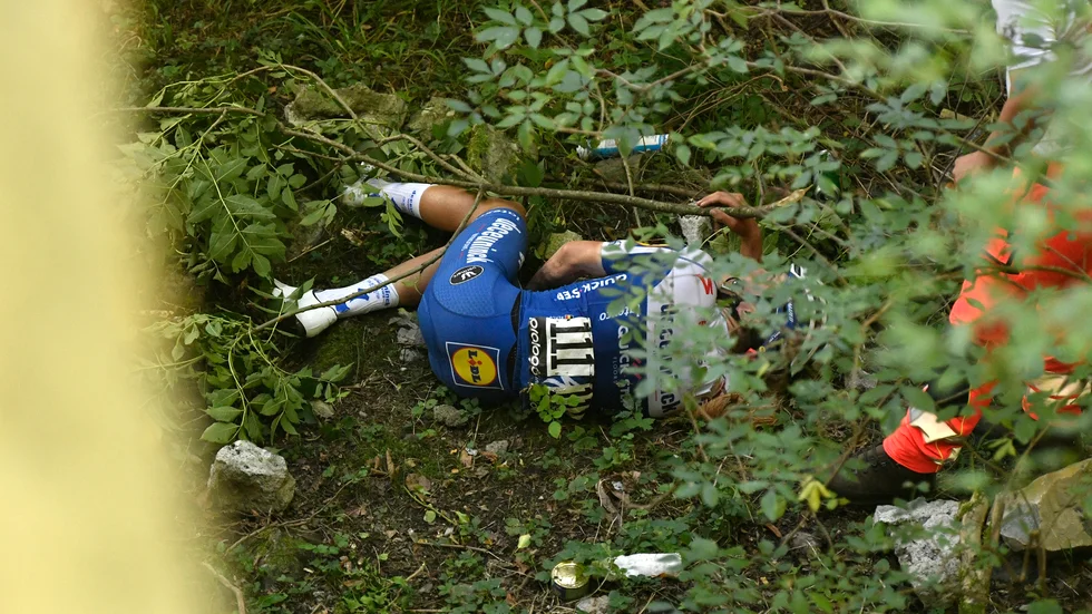 Remco Evenepoel ligger på marken efter att ha kraschat ned i en ravin i Lombardiet runt på lördagen.