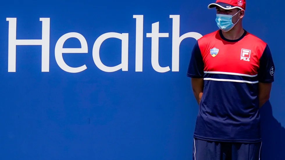 En bollkalle med munskydd följer spelet i uppvärmningsturneringen inför måndagens US Open-start. På söndagen meddelade arrangören att en spelare har testats positivt för covid-19 och stryks ur startfältet. Arkivbild.
