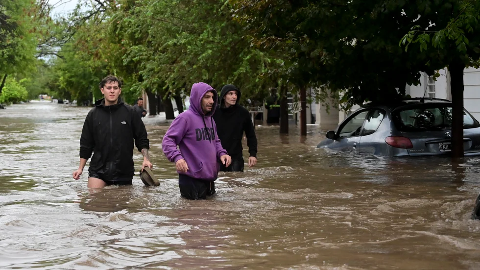 Människor vadar längs en översvämmad gata i argentinska Bahía Blanca, en hamnstad med 350|000 invånare, på fredagen.
