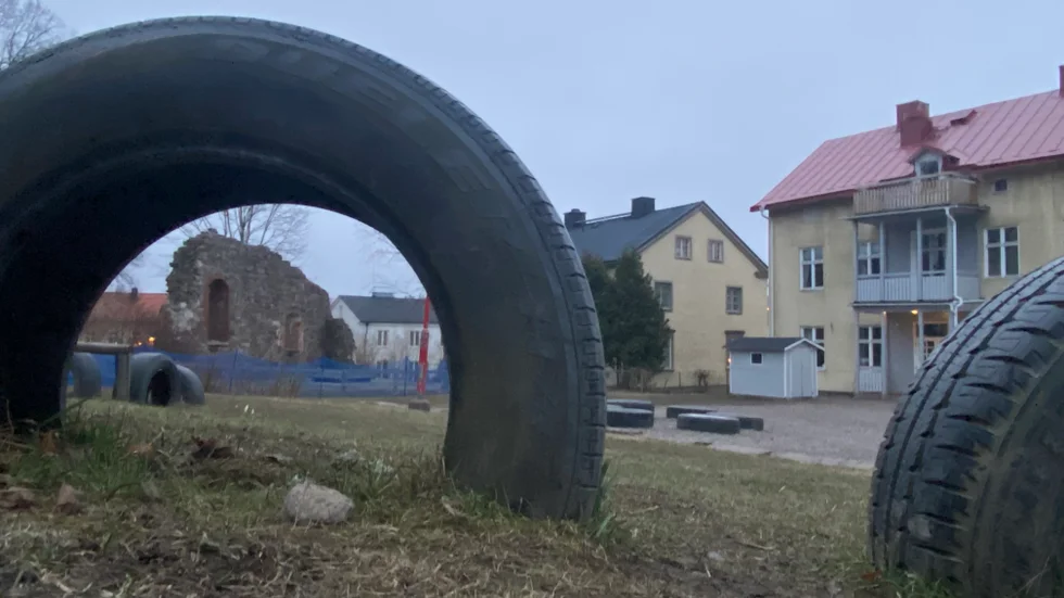 Kyrkoruinen syns i bildäcket på skolgården. Till höger syns en av skolbyggnaderna.