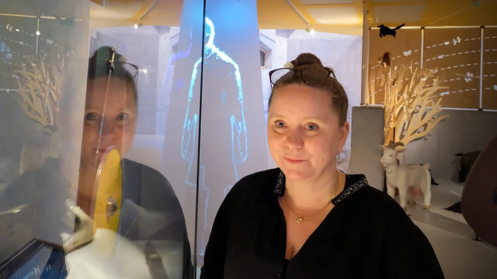 Linda Klementsson, enhetschef Gamla Uppsala museum. Bakom henne skymtar en skärm med en animerad Beowulf. 