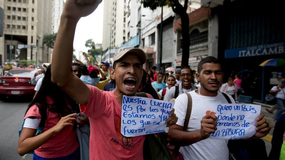 Demonstranter i Venezuela. Mannen till höger önskar sig ett land där befolkningen inte behöver äta från soporna.