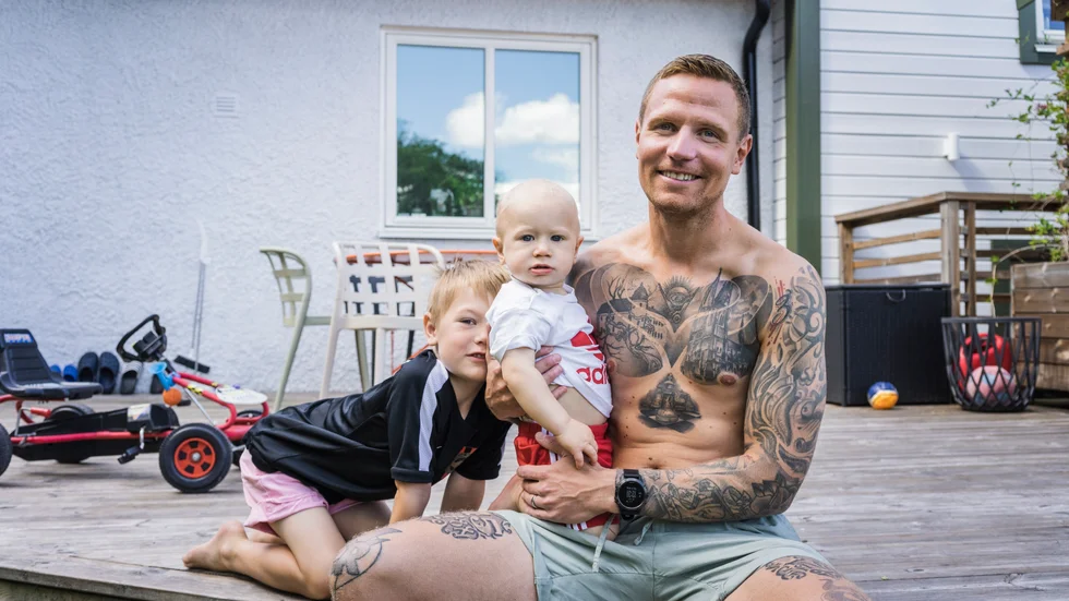 Carl-Johan Roxberg hyllar sin hemstad med Domkyrkan och Uppsala slott över hela bröstkorgen. Här sitter han med sönerna Noa, sex år, och Colin, ett år, utanför hemmet i Bergsbrunna.